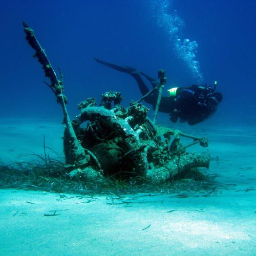 wreck in the depht of the sea with diver swimming around